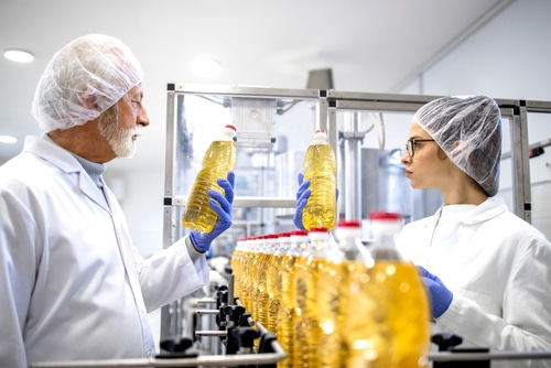 Food factory workers or doing visual quality control of the bottled cooking oil in production plant