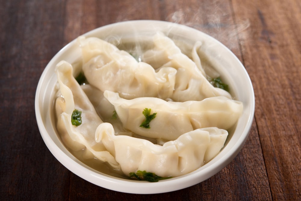 Fresh dumplings soup on plate with hot steams