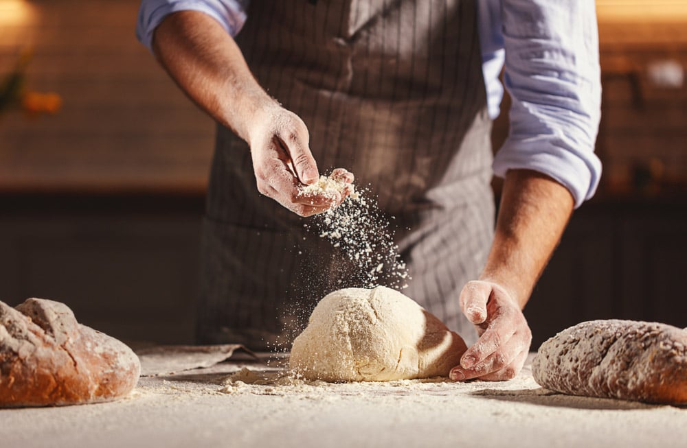Hands of the baker's male knead dough