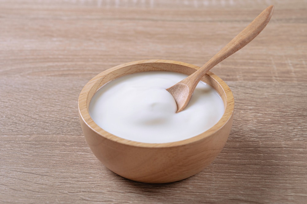 Homemade sour cream yogurt in wooden bowl on table