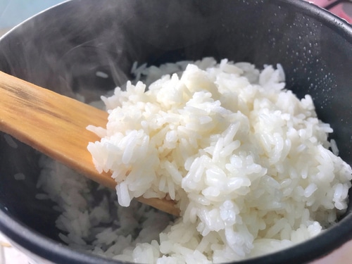 Hot cooked rice, a pot with a brown wooden spoon was scooping up the rice