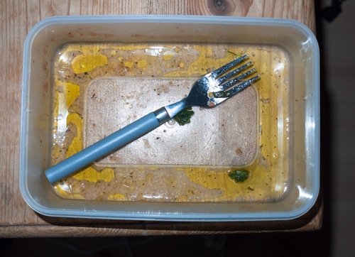 Leftovers eaten and dirty Tupperware and fork empty unclean