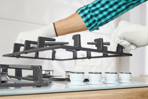 Male hand do installation grill on gas hob in kitchen