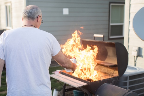 Mature man lighting barbecue with lighter fluid