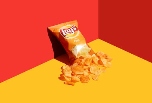 Open packet of Lays chips on a red-yellow background