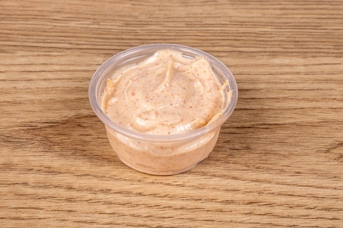 A plastic restaurant serving of a chipotle mayo dipping sauce