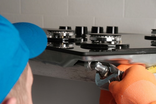 Serviceman installs gas hob in kitchen