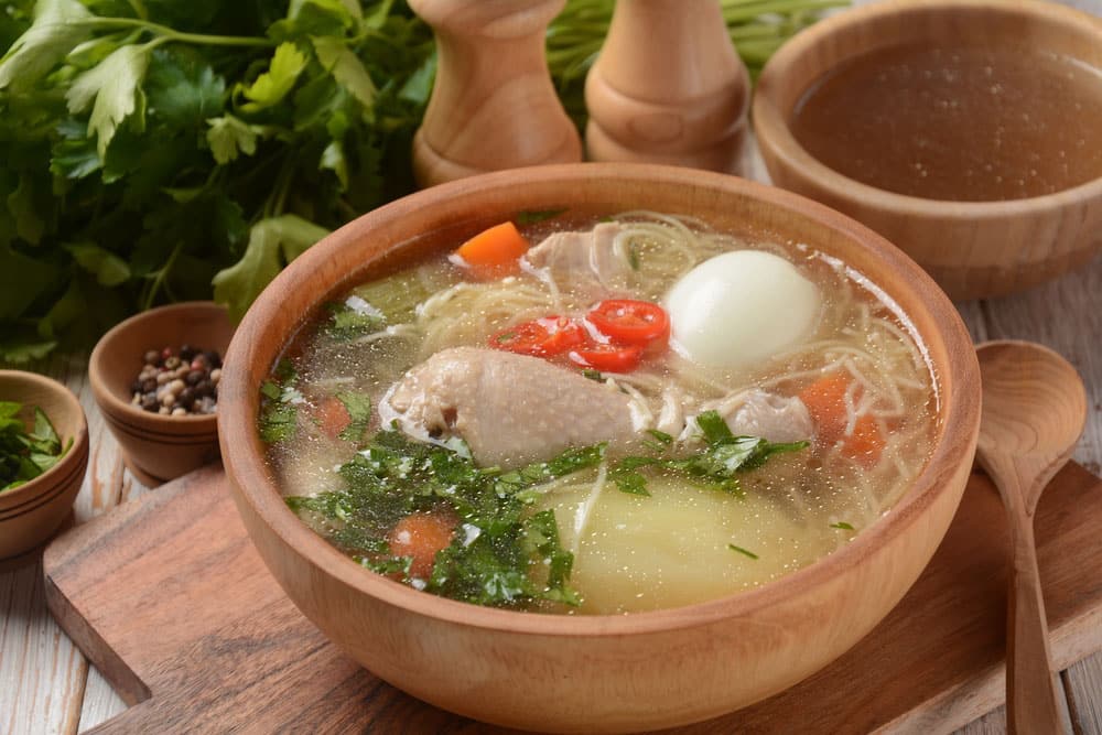 South American Caldo de Gallina chicken noodle soup with boiled egg and herbs