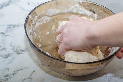 Thick dough is manually mixed in a transparent bowl