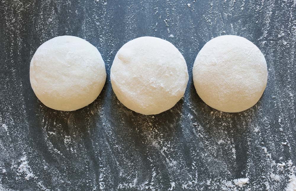 Three balls of fresh homemade wheat dough on kitchen table
