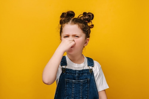 Unhappy sad little preschool girl kid feeling bad and dislike smell and hold nose