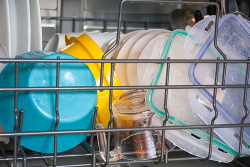 View of bottom rack of dishwasher loaded with plastic ware