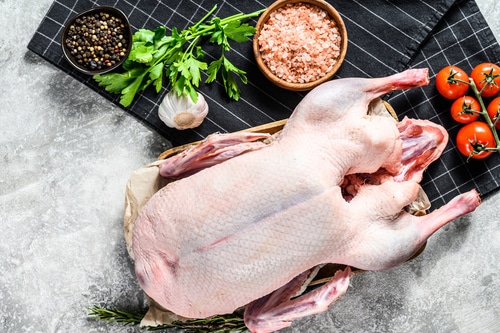 Whole raw goose. Recipe for cooking with pink salt, garlic, parsley and rosemary