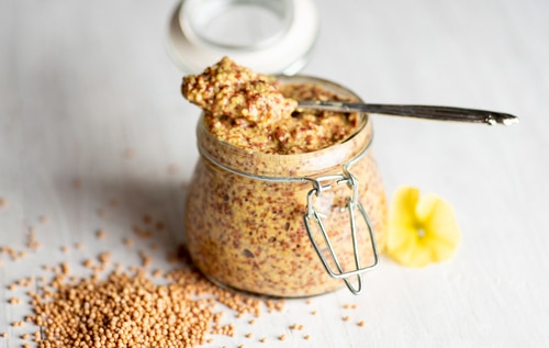 Wholegrain mustard in a jar on a table closeup