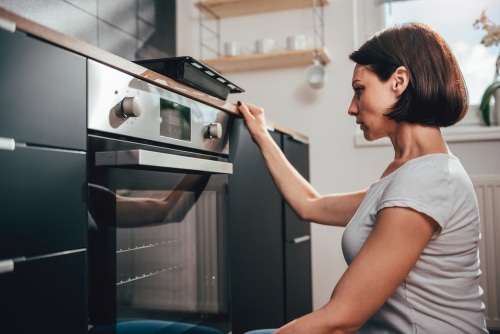 Woman wearing white shirt using oven