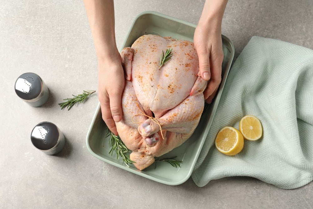 Woman preparing whole turkey at table