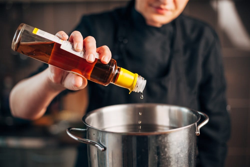 chef pouring vinegar in a pot with water