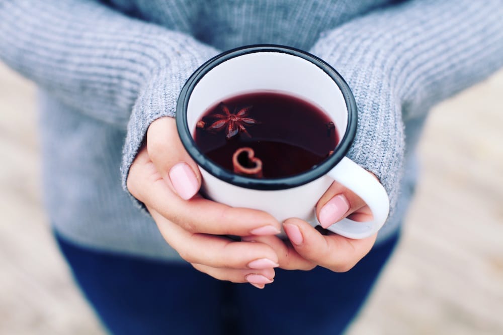 holding metal mug with mulled wine