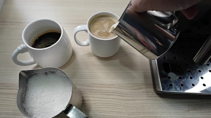 Pouring steamed milk into coffee mug Pouring steamed milk into coffee mug