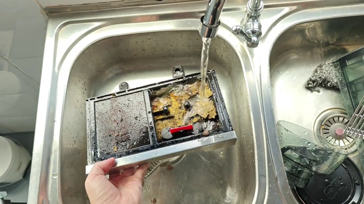 Rinsing rectangular dishwasher filter under tap Rinsing rectangular dishwasher filter under tap