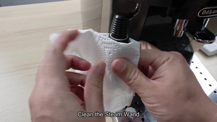 Wiping down the steam wand with a paper towel Wiping down the steam wand with a paper towel