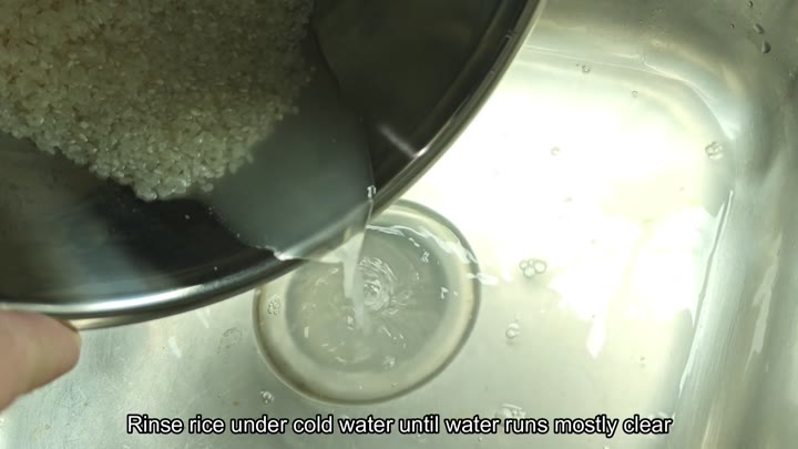 Draining rinsed rice in a metal bowl Draining rinsed rice in a metal bowl