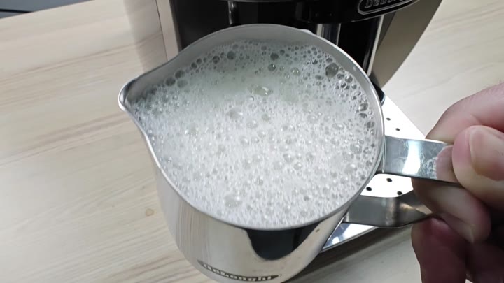 Pitcher filled with aerated frothy milk Pitcher filled with aerated frothy milk
