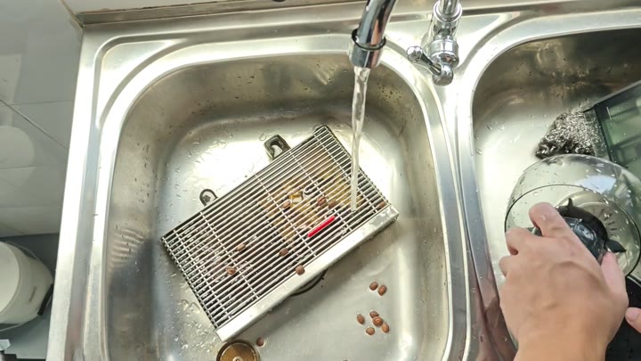 Rinsing coffee beans and parts in sink Rinsing coffee beans and parts in sink