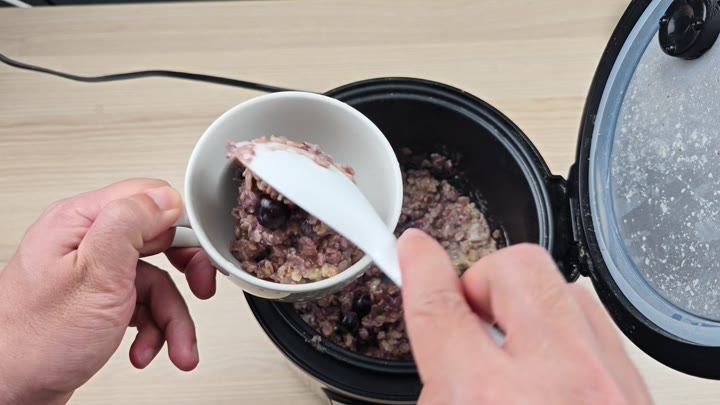 Serving blueberry oatmeal into a mug Serving blueberry oatmeal into a mug