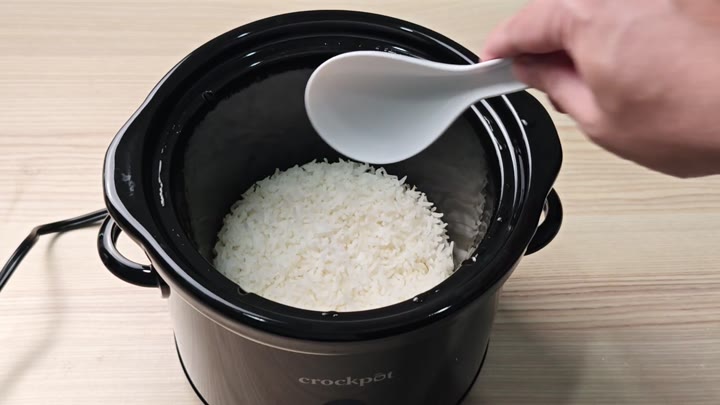 Spoon serving cooked rice from Crockpot Spoon serving cooked rice from Crockpot
